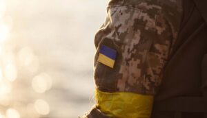 En arm i militärkläder med en ukrainsk flagga på ärmen